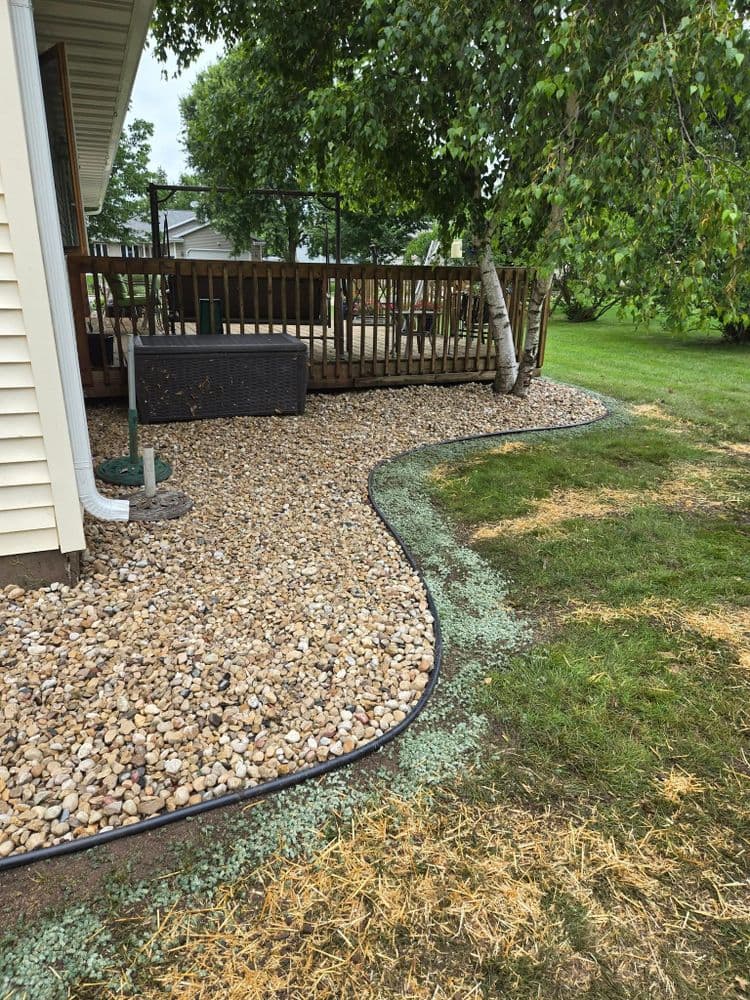 Landscaped backyard with a gravel path and wooden deck surrounded by greenery.